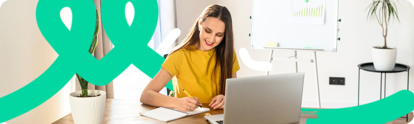 Femme devant un ordinateur qui écrit sur un bloc note 